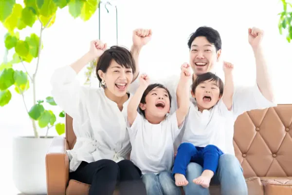 両手を上げて楽しそうにポーズを取る2人の子どもとその両親