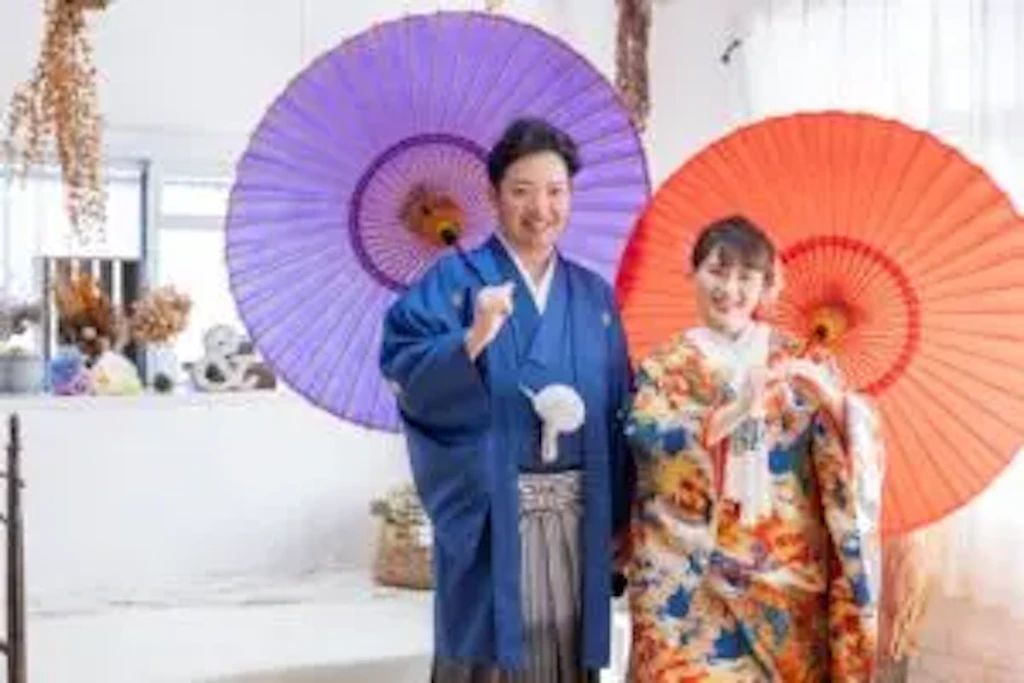 岡山のスタジオで紫と赤の和傘の前に立つ新郎新婦様のフォトウェディング撮影の様子