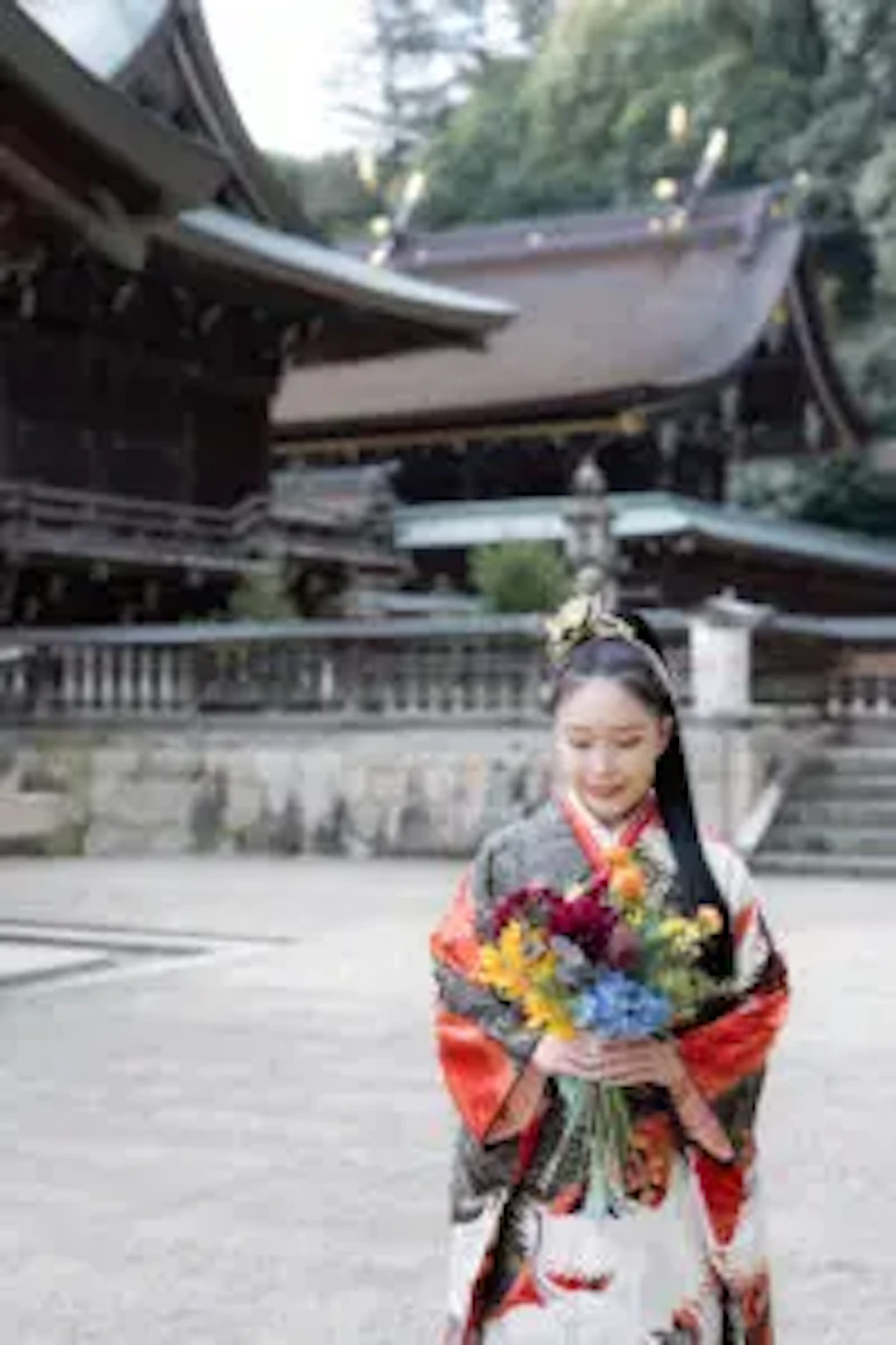 吉備津彦神社の社殿を背景に成人式の振袖姿でカラフルな花束を手にする女性