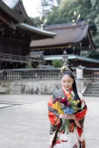 吉備津彦神社の社殿を背景に成人式の振袖姿でカラフルな花束を手にする女性