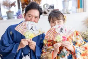 岡山のスタジオで扇子を手に微笑む新郎新婦様のフォトウェディングの記念撮影