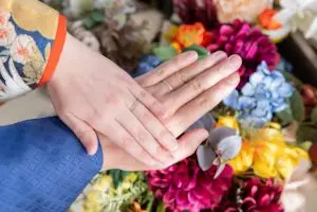 花々に囲まれながら結婚指輪を重ねる新郎新婦様の手元のクローズアップ写真