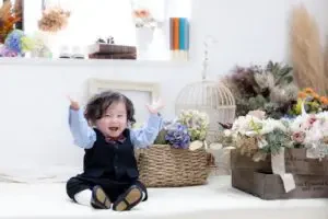 岡山のスタジオで、お花に囲まれながら両手を上げて満面の笑みを見せる1歳の男の子