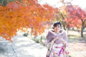岡山後楽園の燃えるような紅葉の中、ファーストールを羽織る成人式の前撮りの振袖姿のお嬢様