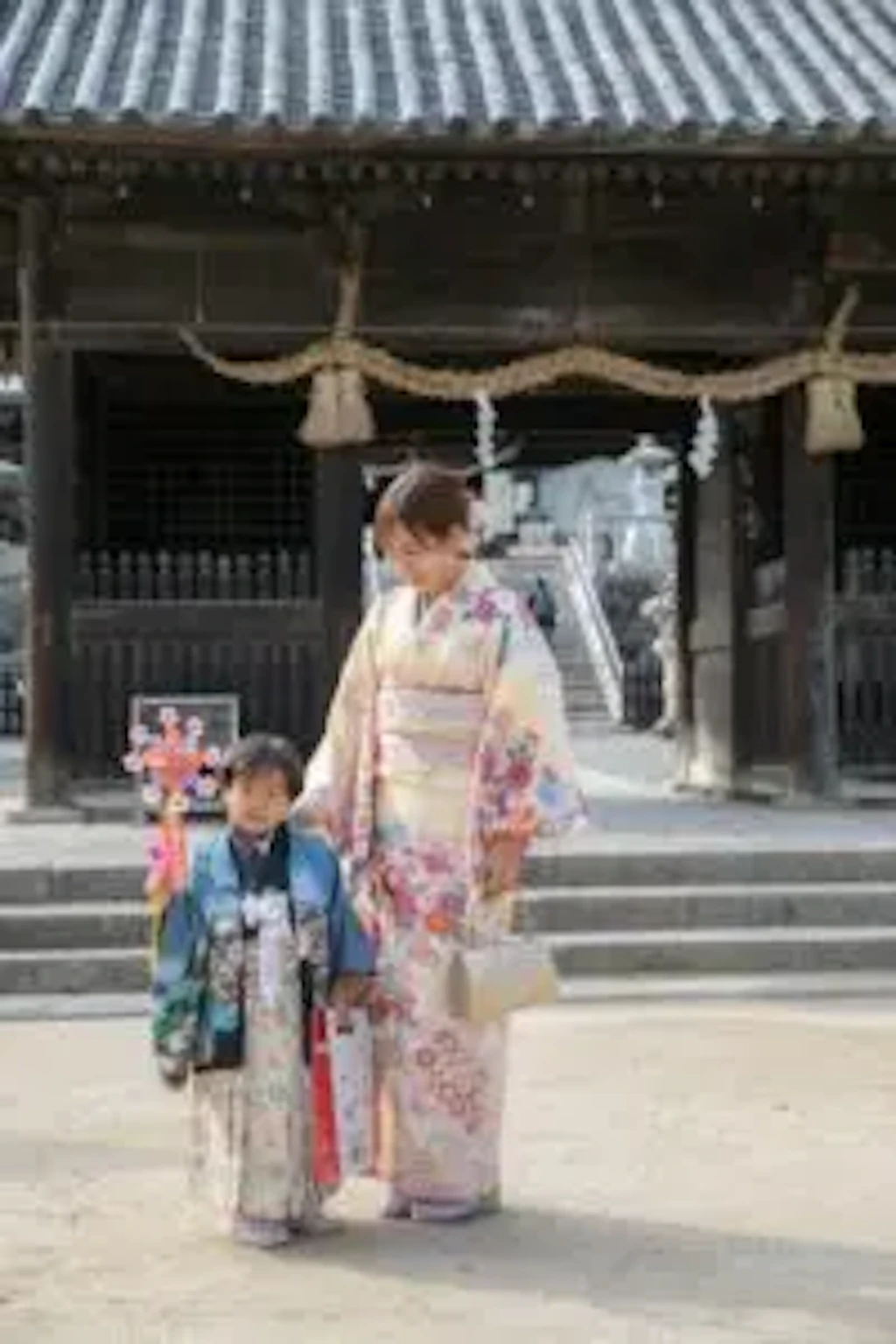 吉備津彦神社の境内で、お母様と手をつないで並んで歩く七五三の女の子