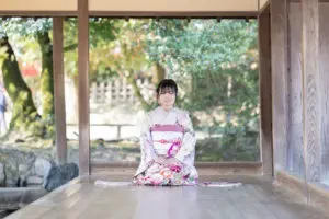 岡山後楽園の縁側に腰を下ろし、正座の姿勢で佇む成人式の前撮り撮影中の振袖姿のお嬢様