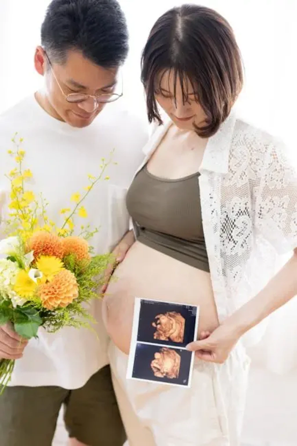 岡山のフォトスタジオで、二人並んでエコー写真を覗き込むマタニティ姿の奥様とご主人様