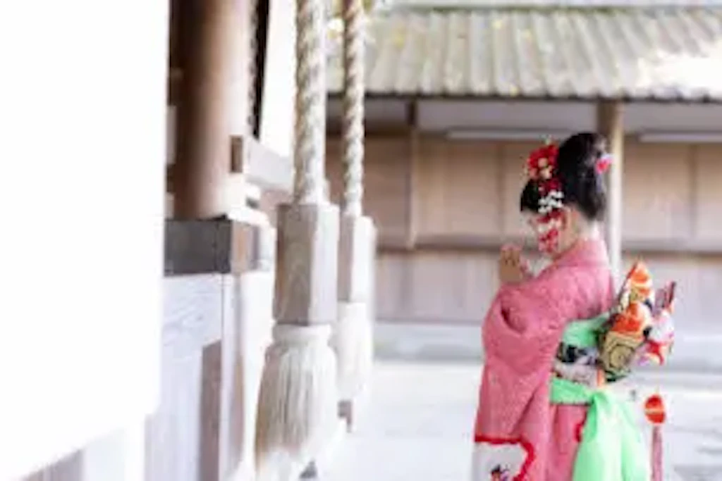 吉備津神社の本殿前で、後ろ姿の女の子が両手を合わせて静かに祈る七五三の一コマ