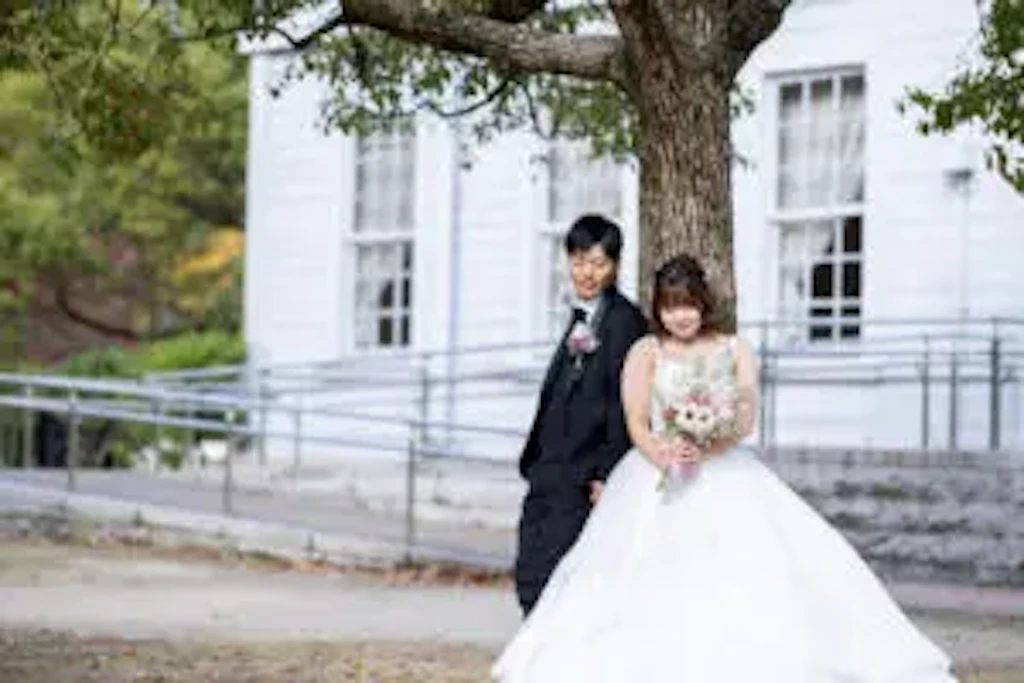 木の下で新婦様に寄り添う新郎様と笑顔のブーケショット