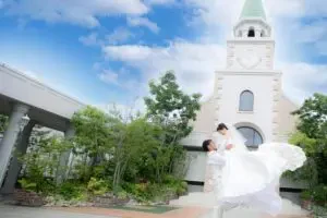 チャペルの外でウェディングドレス姿の新婦を抱っこする新郎