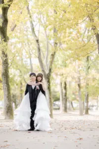 紅葉の並木道で手を取り合い正面を向く新郎新婦様の記念写真