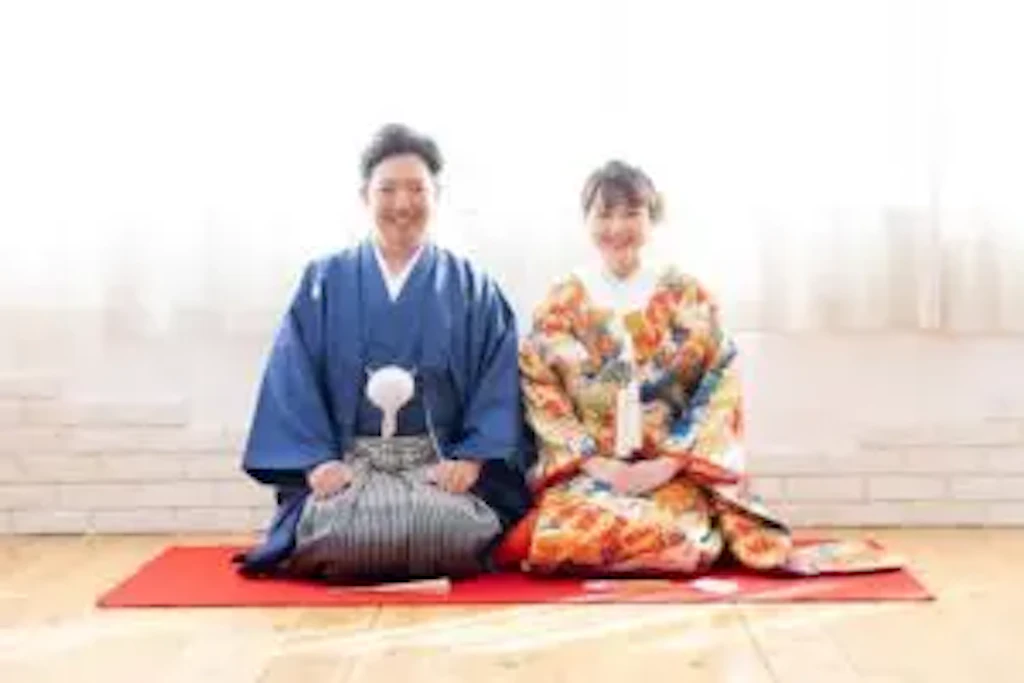 岡山のスタジオで青の紋付袴と色打掛を着た新郎新婦様が並んで座るフォトウェディングの一枚