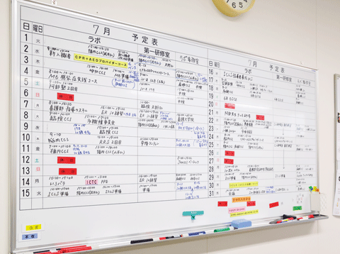シミュレーションセンター事務室に掛けられた予定表。スケジュールがびっしり書き込まれている