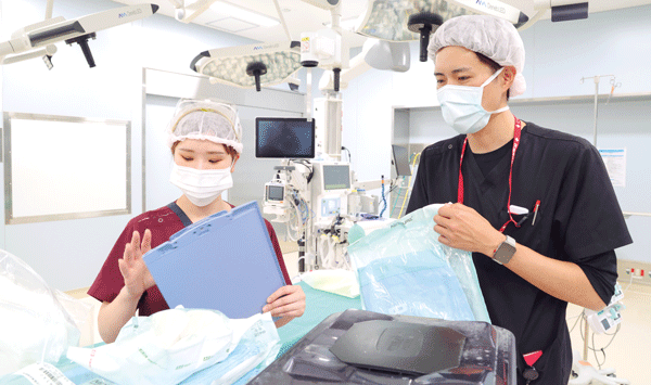 器械出し担当の臨床工学技士は看護師とともに器械の準備にもあたる(右が弘田さん)