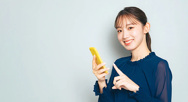 スマホを持ち微笑む女性