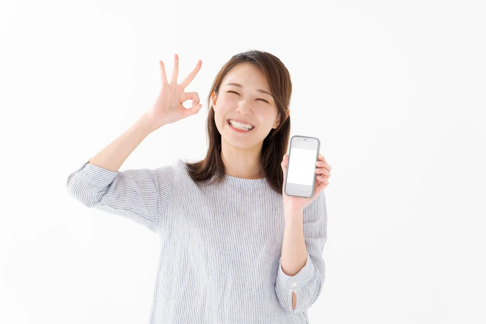 スマホを持ちOKマークを示す女性