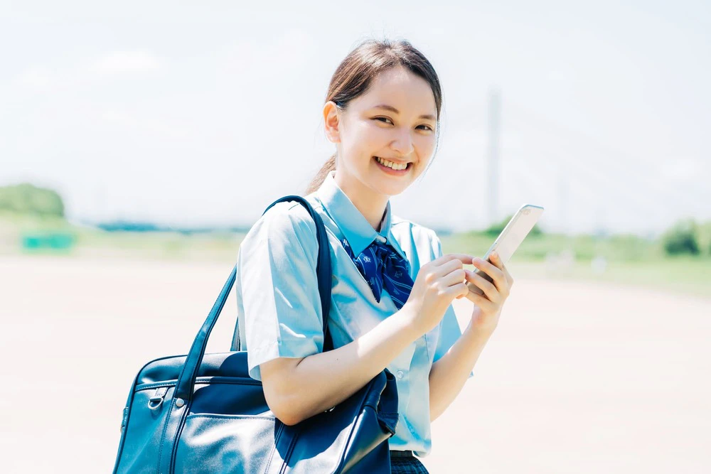 スマホを持つ笑顔の女子高生