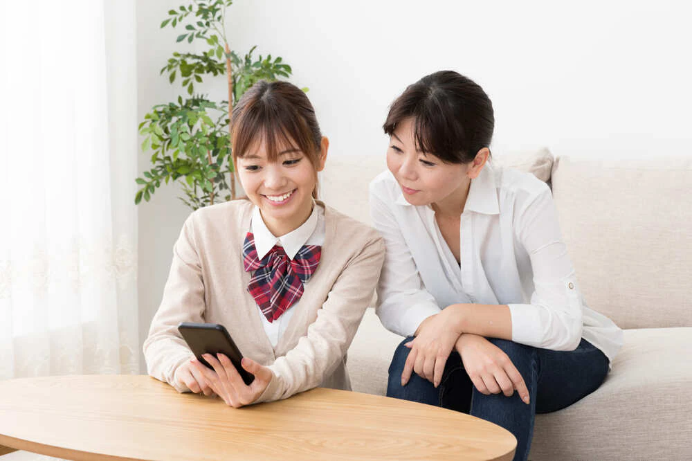 スマホを楽しむ女子高校生とその母親