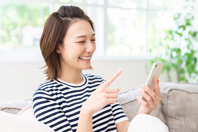 スマホを手に持ちほほえむ女性