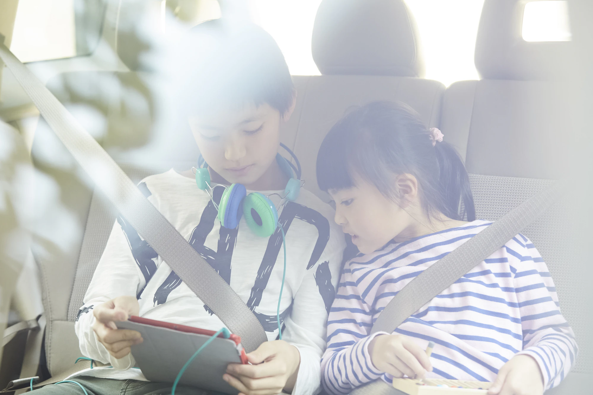 車内でタブレットを見る子ども