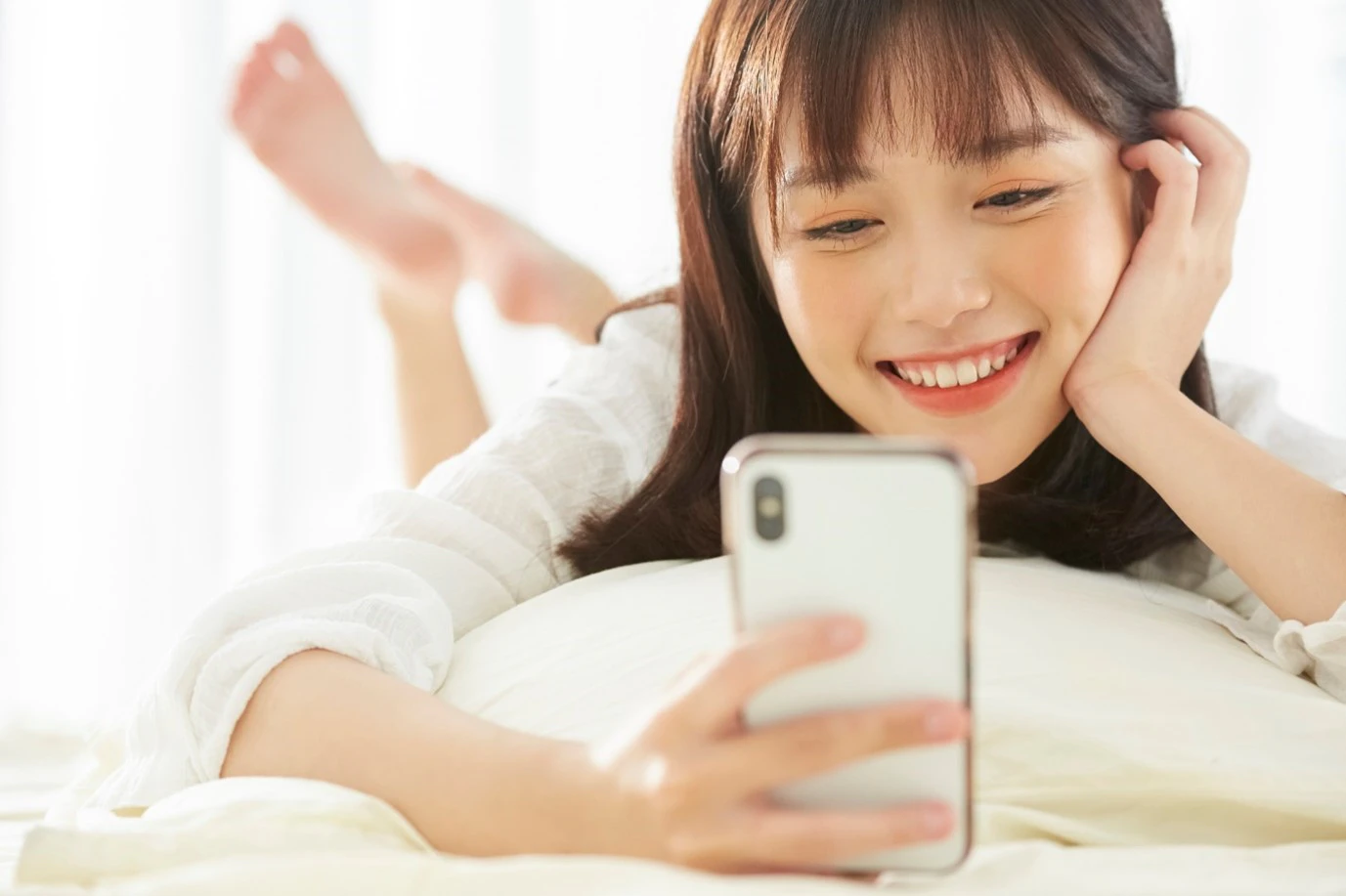 ベッドでスマホを見る女性