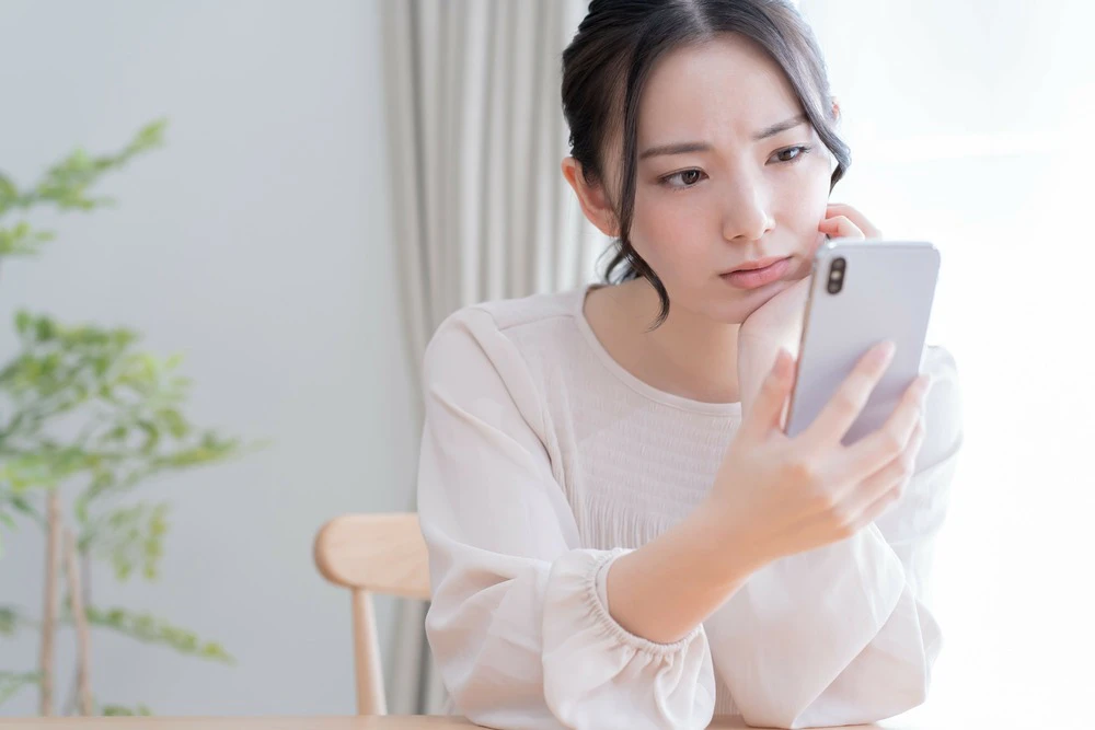 スマホを見て悩む女性