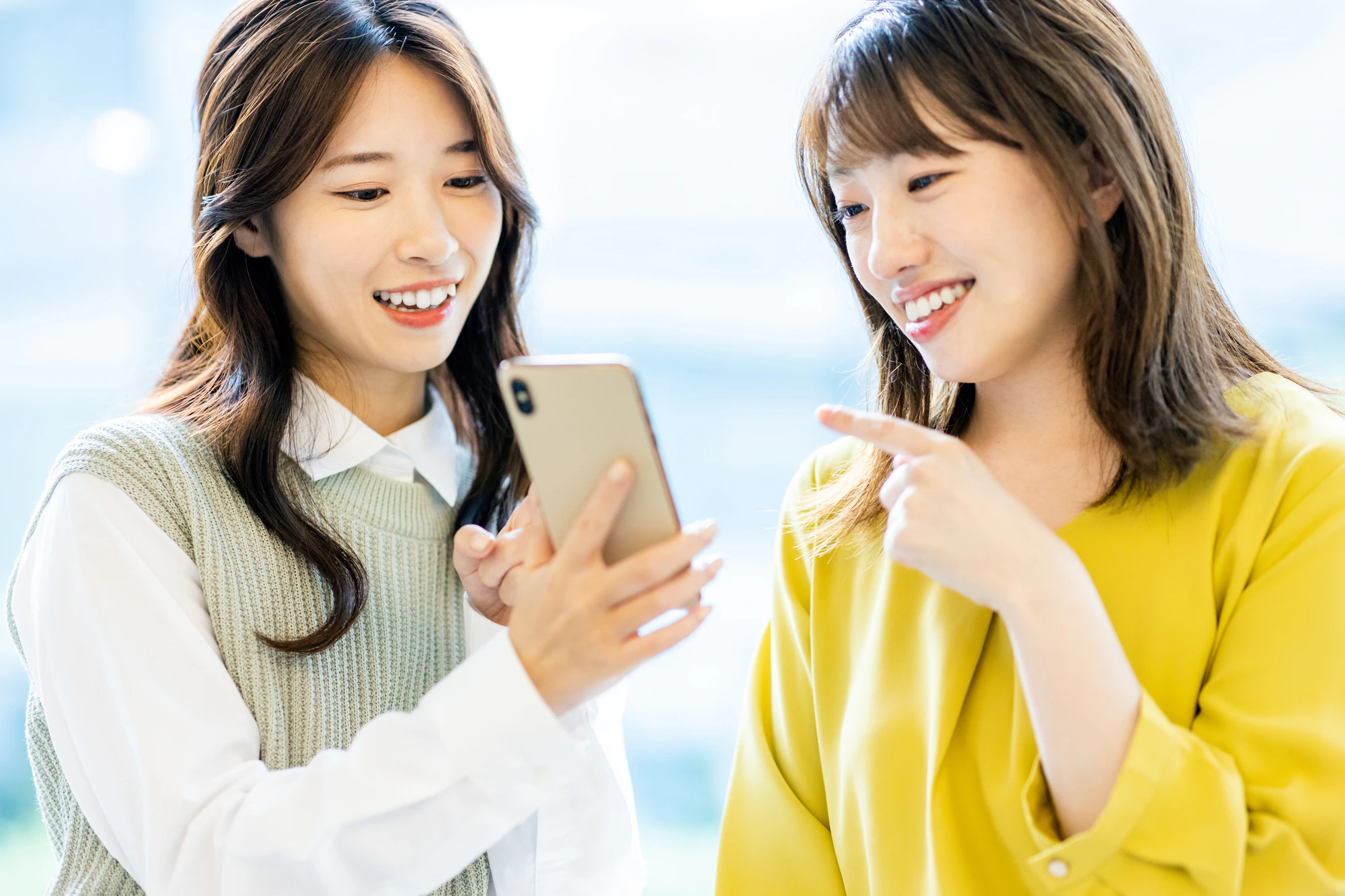 スマホを友人に見せる女性