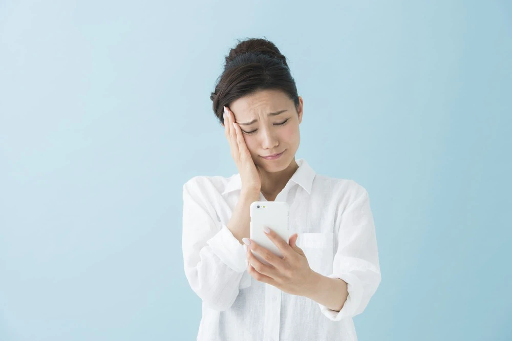 悩みながらスマホを見つめる女性