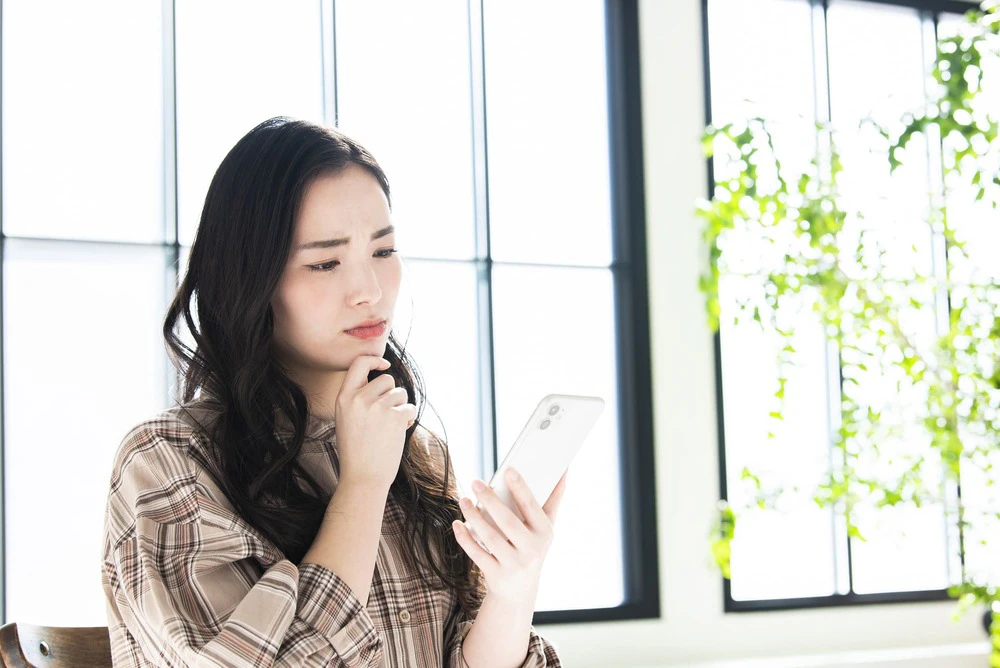 スマホを持ち悩む女性