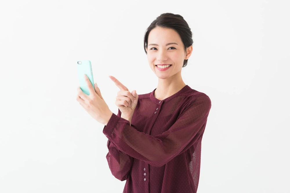 スマホを指さす女性