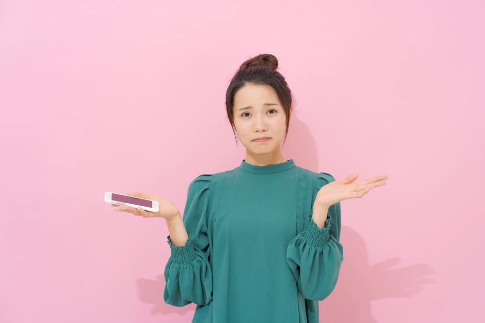 スマホを持ち悩む女性