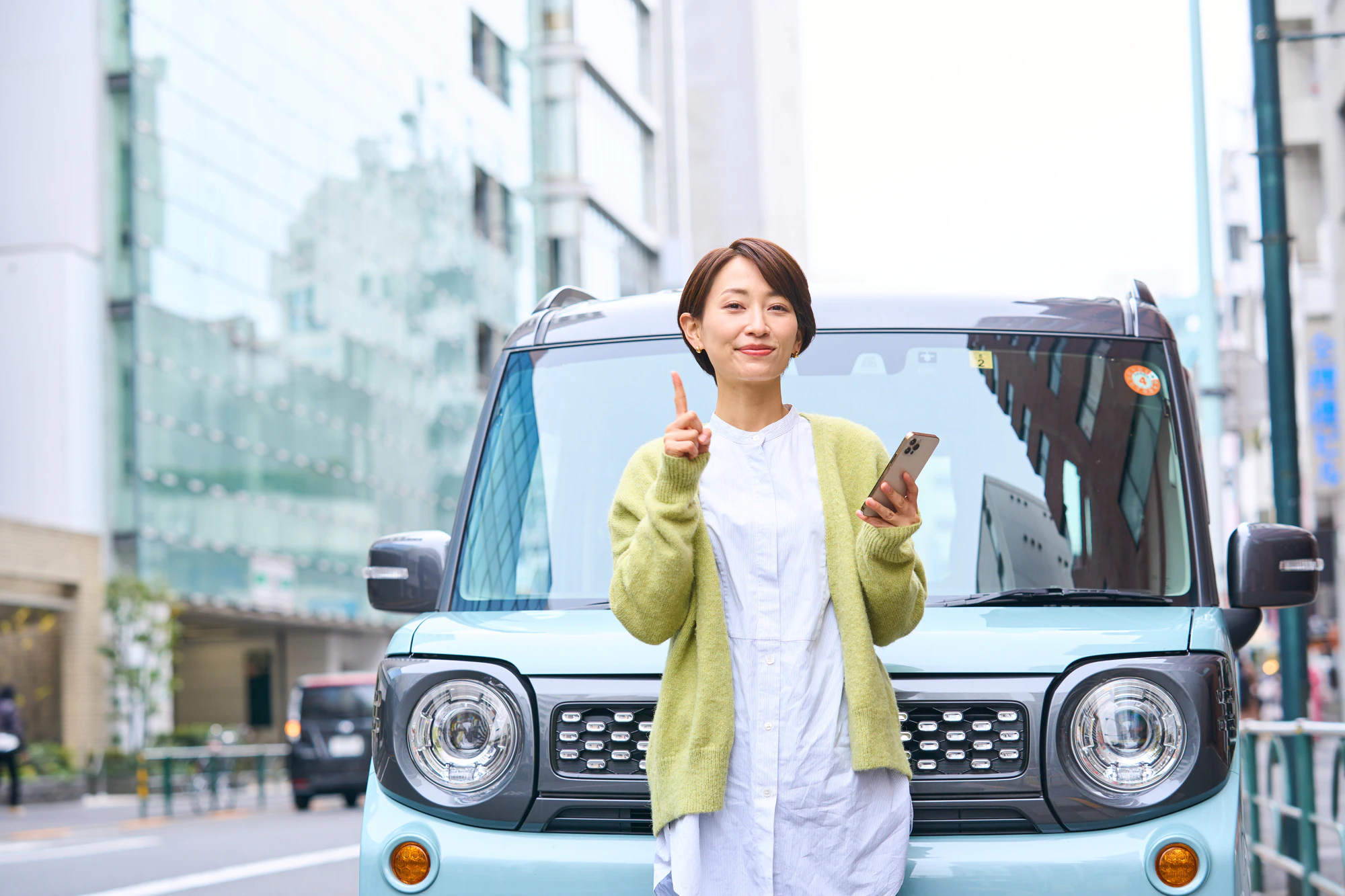 車の前でスマホを持つ女性