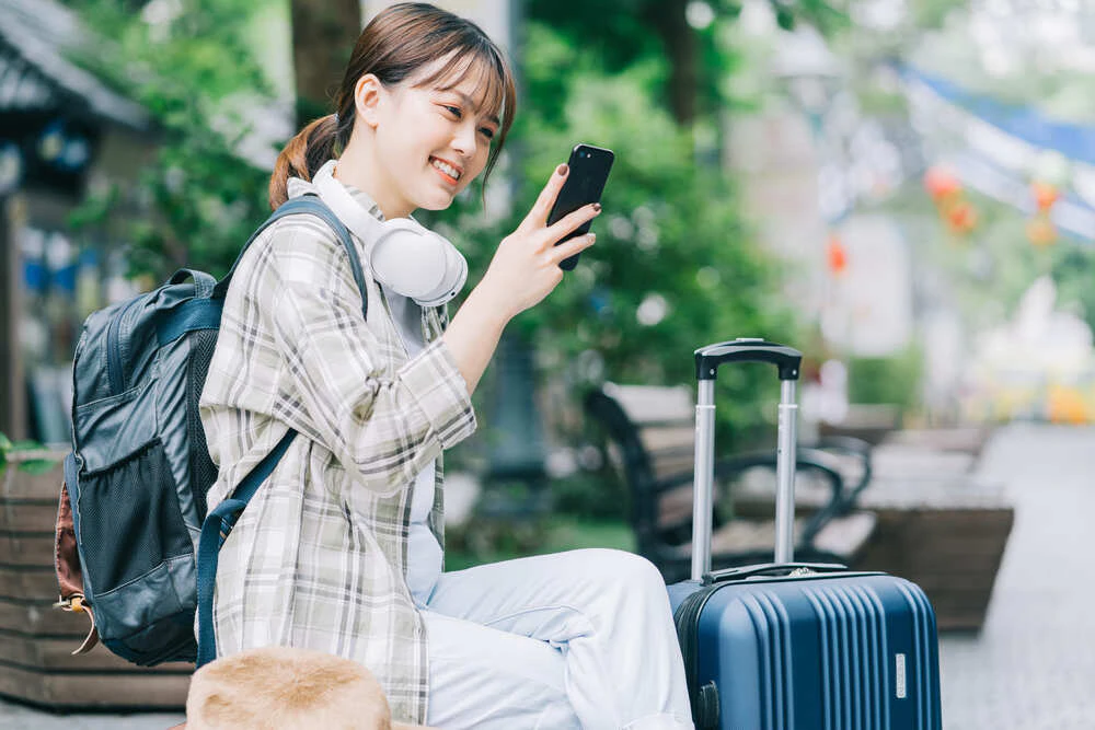 荷物を抱えスマホを楽しむ女性