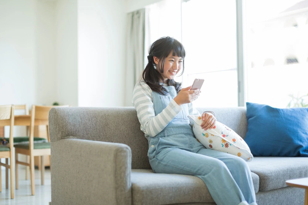 ソファーに座ってスマホを見る女の子