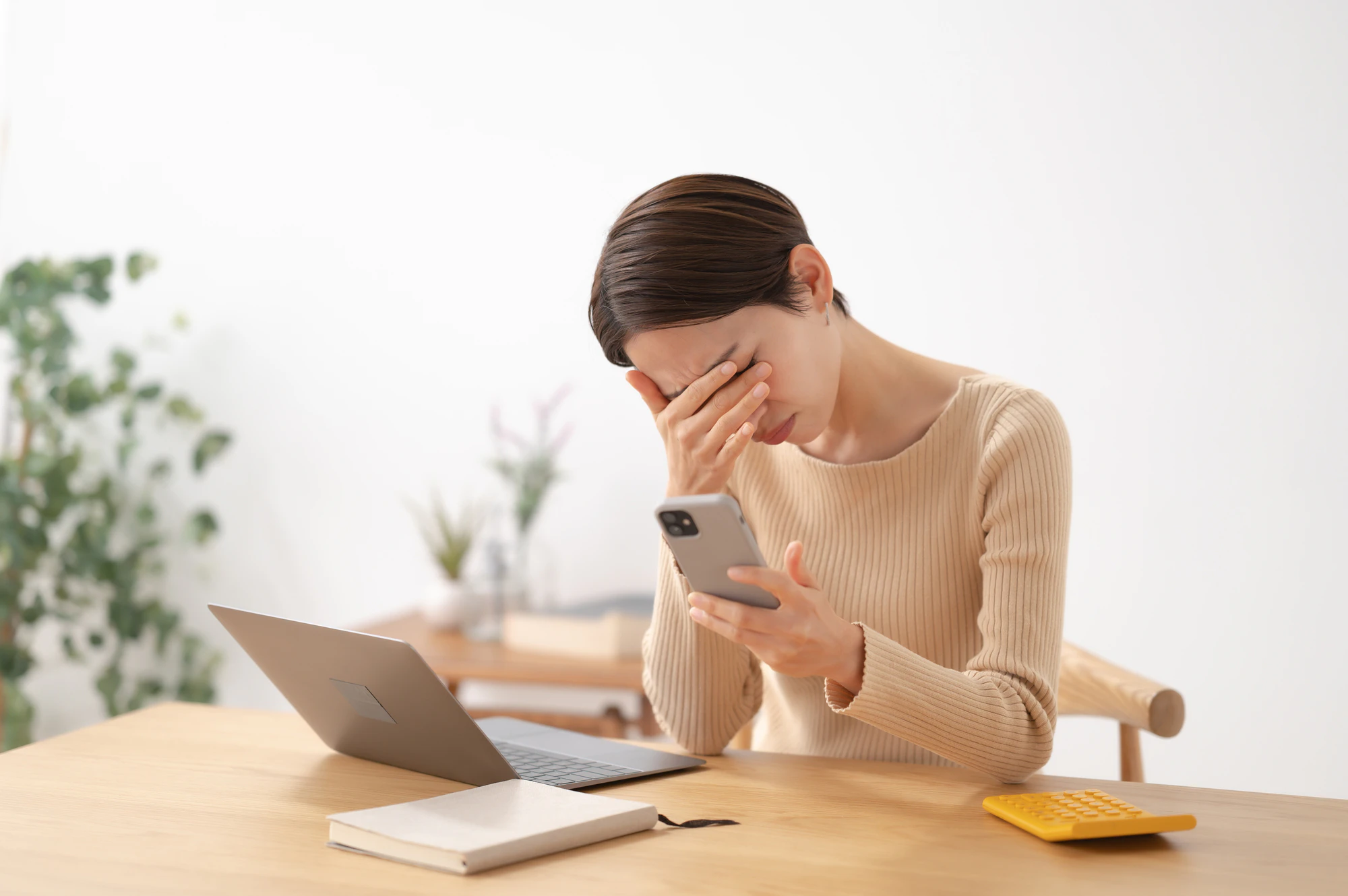 スマホを持って悩む女性