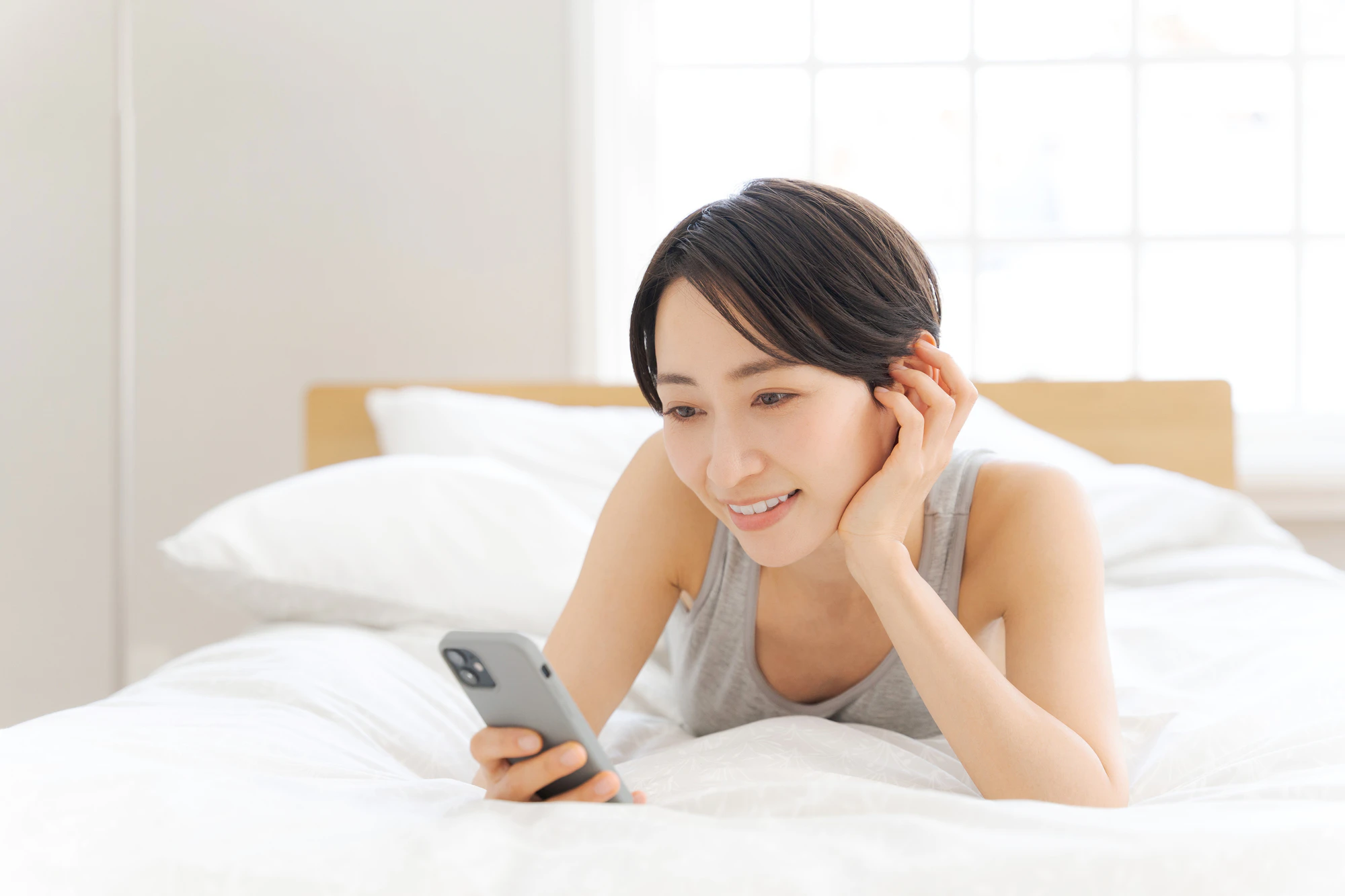 くつろぎながらスマホを見つめる女性