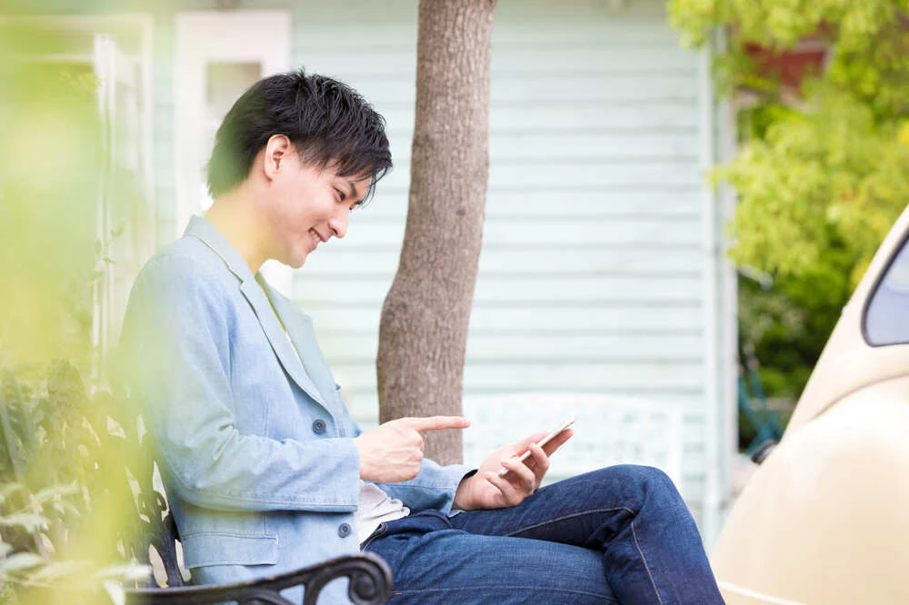 ベンチでスマホを操作する男性