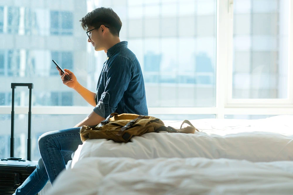 ベッドの上でスマホを触る男性