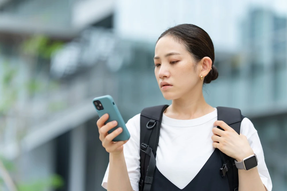 外でスマホを見ている女性