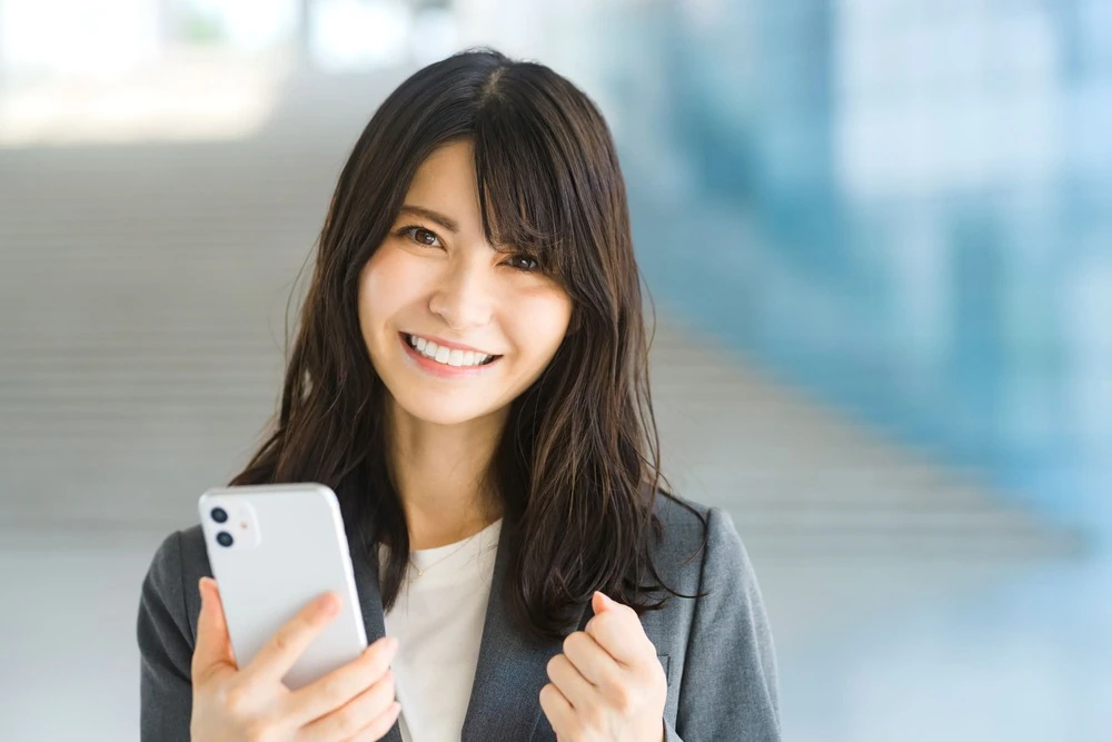 スマホを持ちガッツポーズをする女性