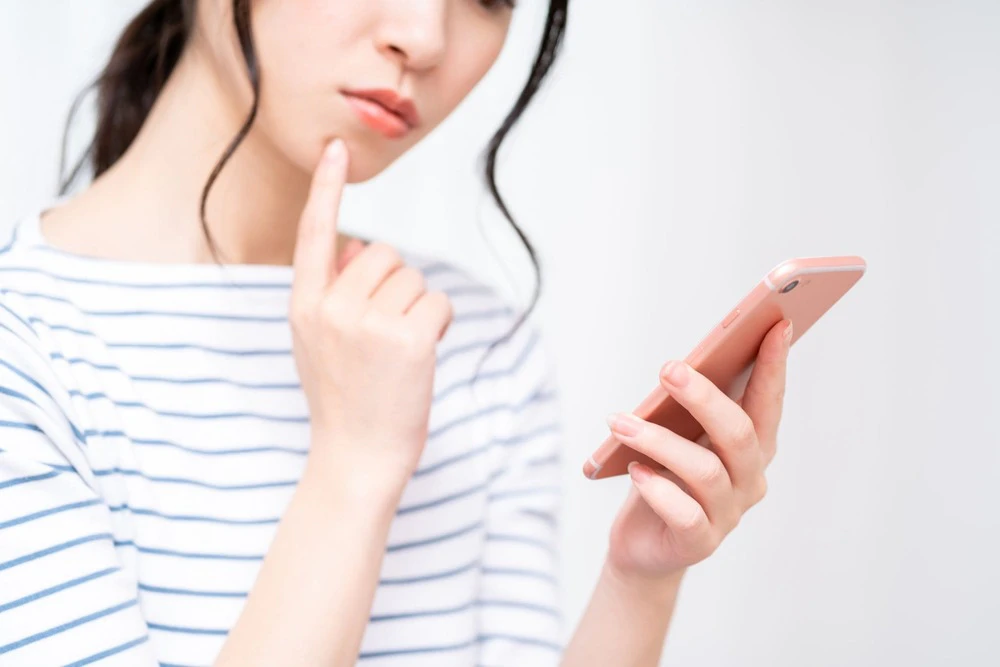 スマホを持ち悩む女性