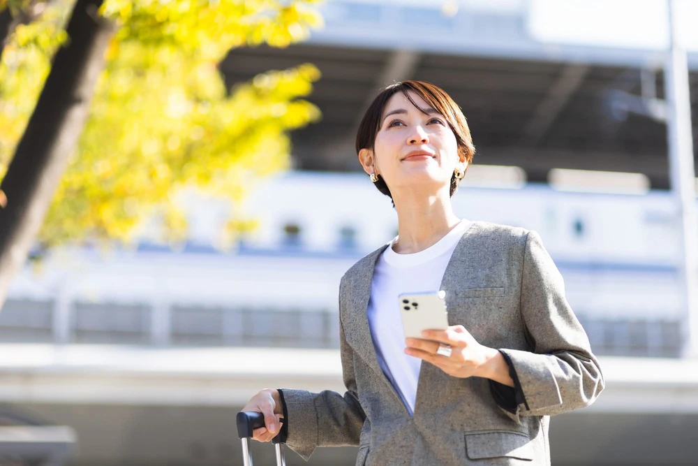 外でスマホを持つ女性