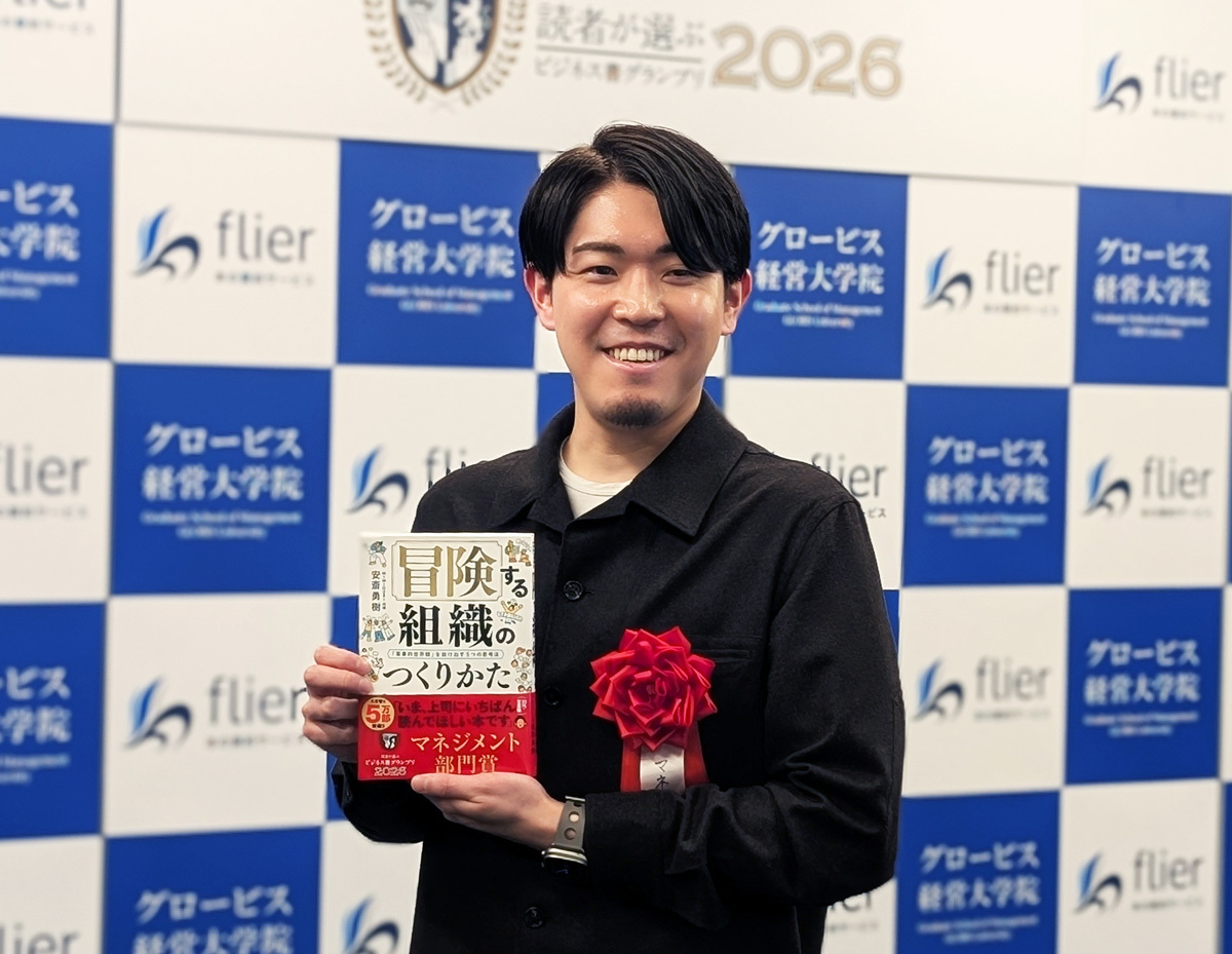 受賞式会場で、本とトロフィーを持った安斎勇樹