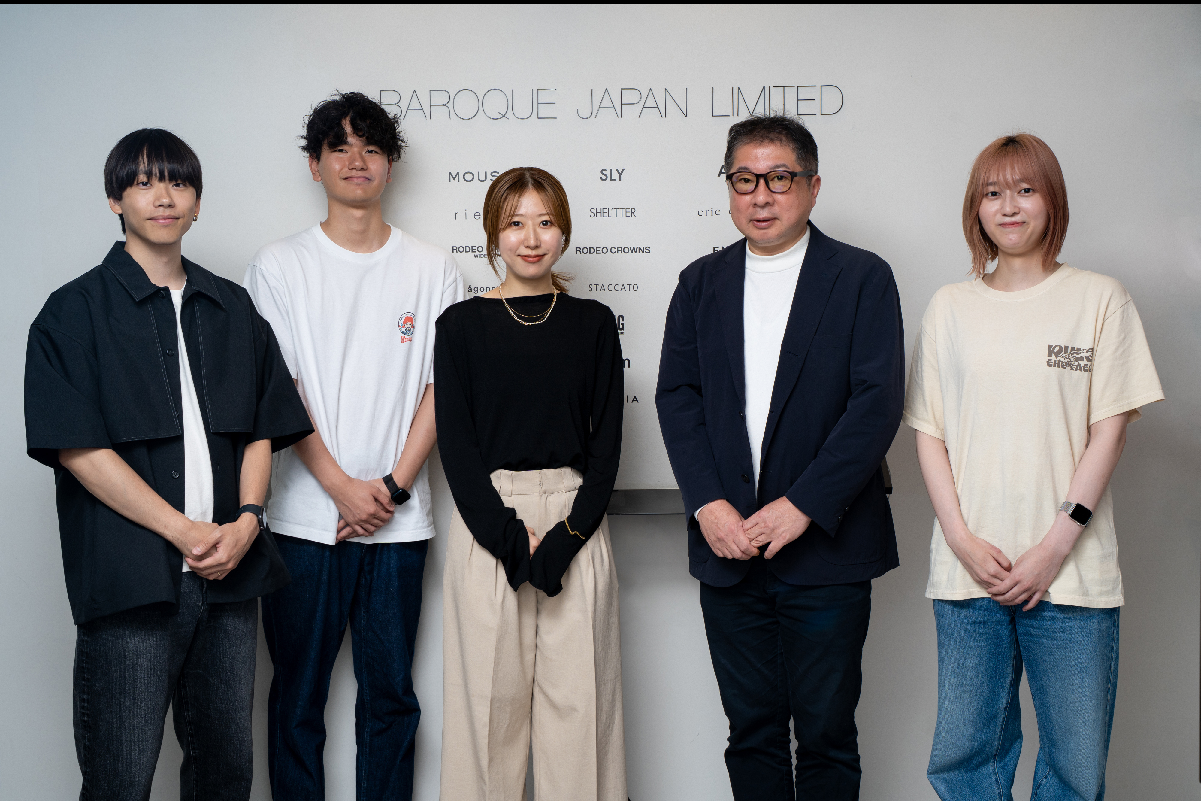 BAROQUE JAPAN LIMITEDの企業ロゴやブランド名が書かれた壁の前に並んで立つ5名