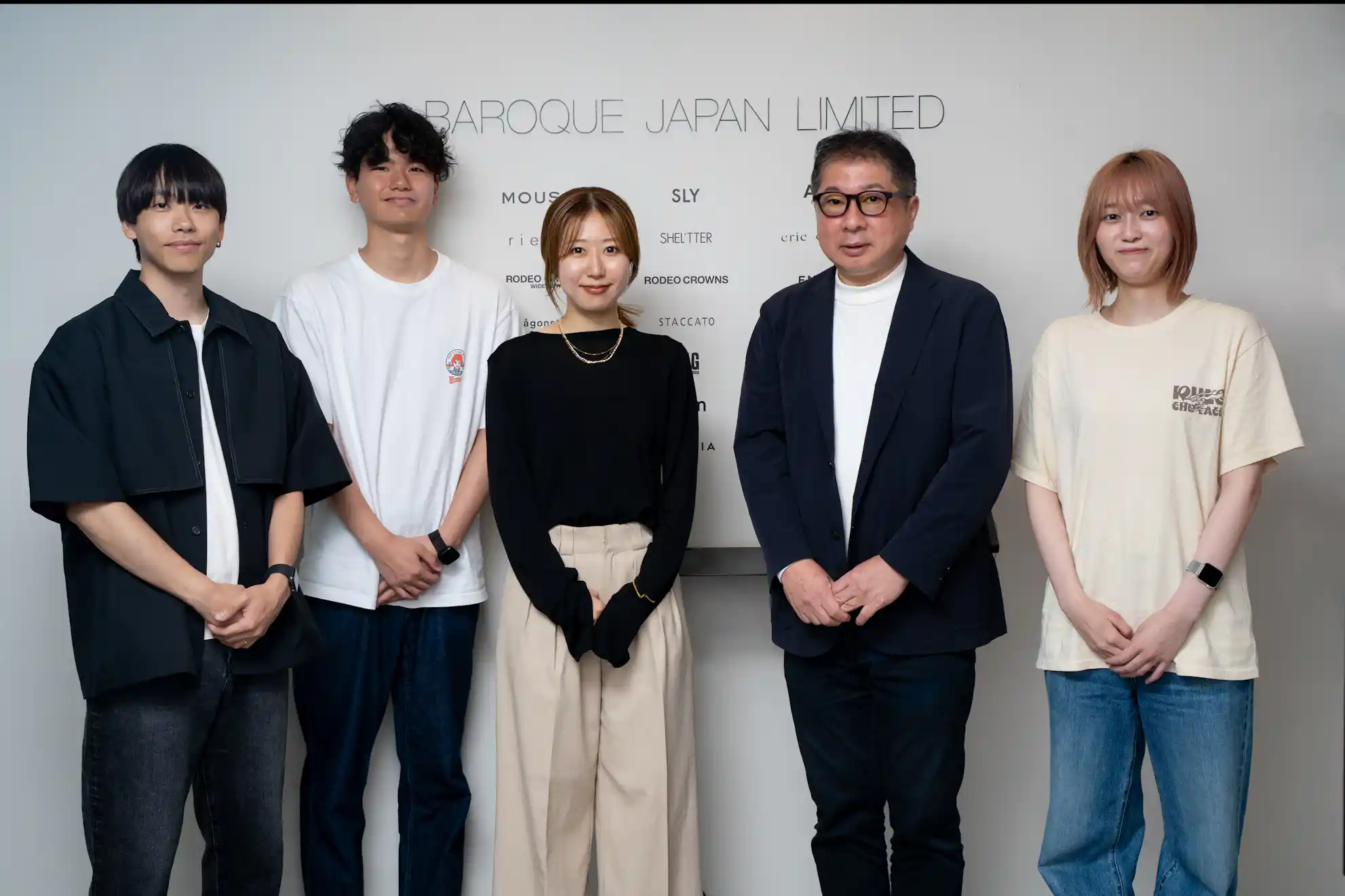 BAROQUE JAPAN LIMITEDの企業ロゴやブランド名が書かれた壁の前に並んで立つ5名