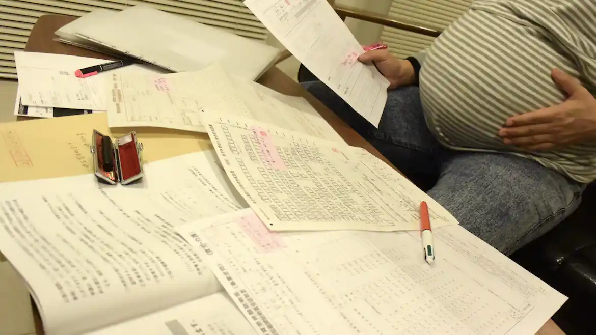 筆者が3年半前に自宅で撮影した写真 テーブルに散らかる書類の前にいる妊婦の姿