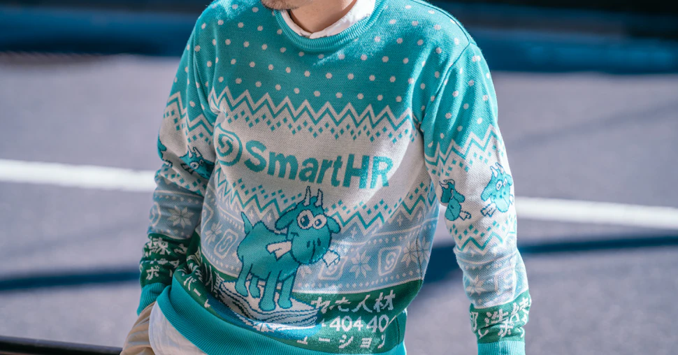 アイキャッチ、SmartHRオリジナルアグリーセーター 「かわいいヤギのセーター」を着用したモデル写真