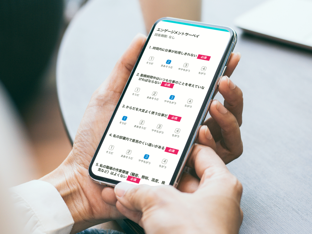スマートフォンを手に持ち、エンゲージメントサーベイの質問項目に回答している利用シーンのイメージ画像。