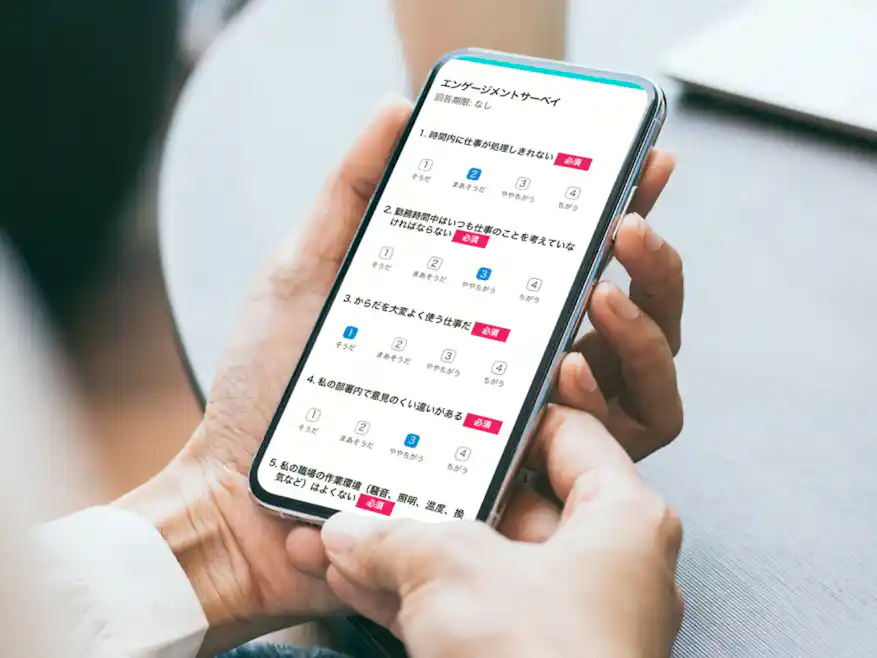スマートフォンを手に持ち、エンゲージメントサーベイの質問項目に回答している利用シーンのイメージ画像。