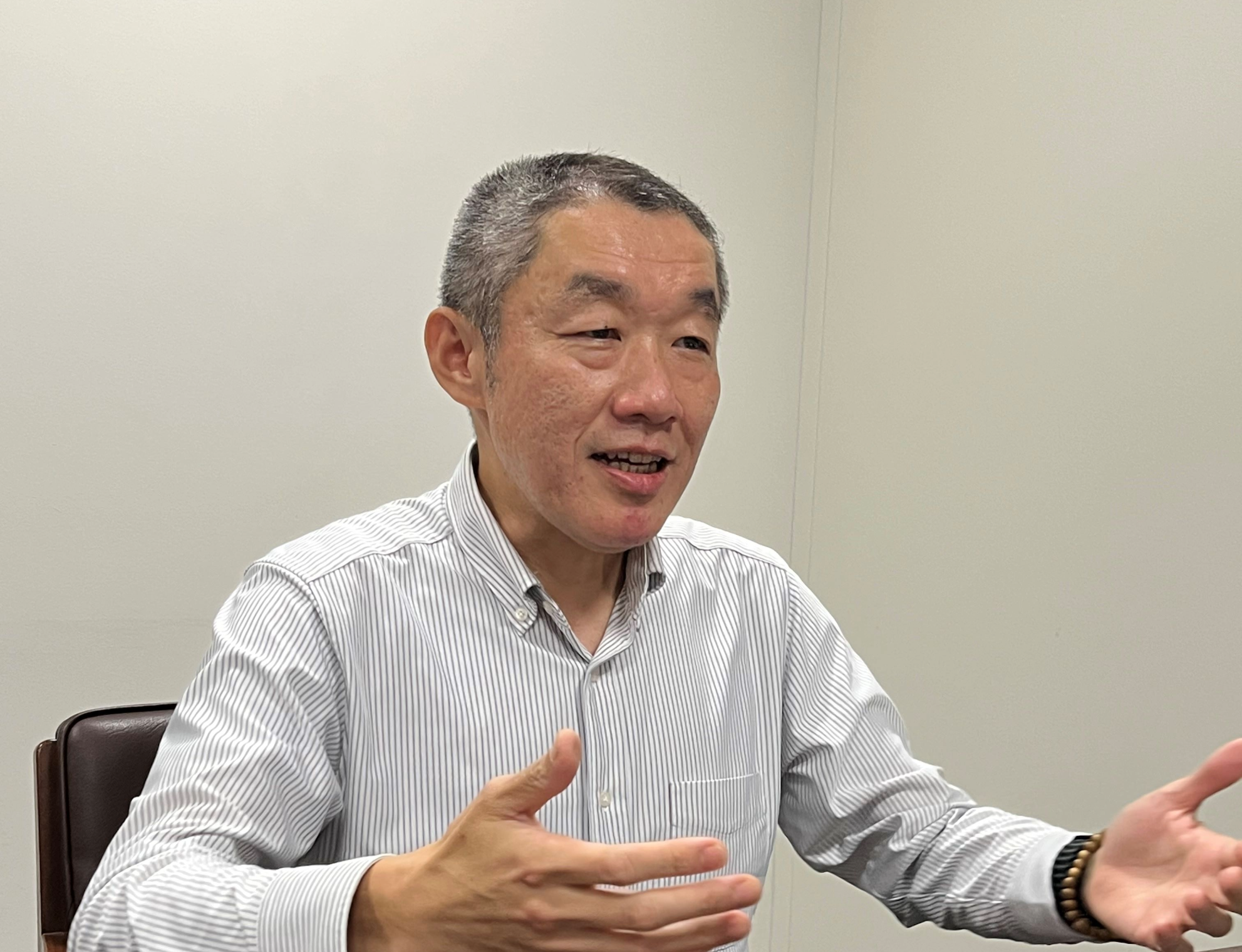 ストライプシャツを着た人事部の佐々木さんが、両手を広げて話をしている写真